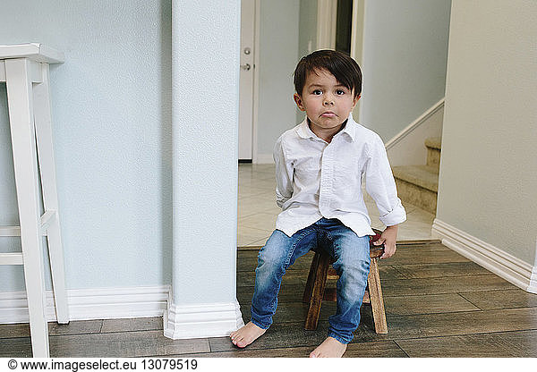 Portrait of cute boy sitting on stool at home