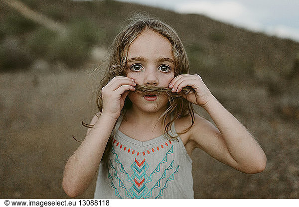 Portrait of cute girl making mustache with her hair