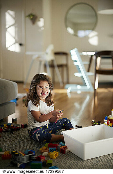 Portrait of cute girl smiling while playing with toys at home