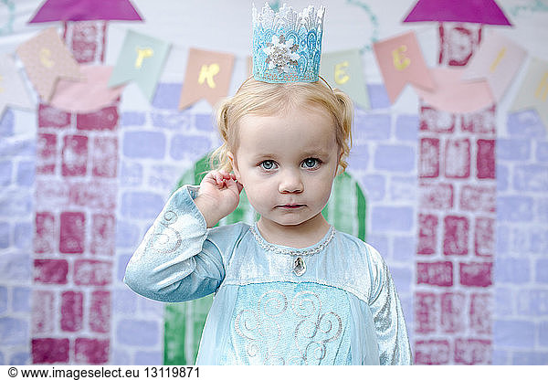 Portrait of cute girl standing against castle painting during princess party