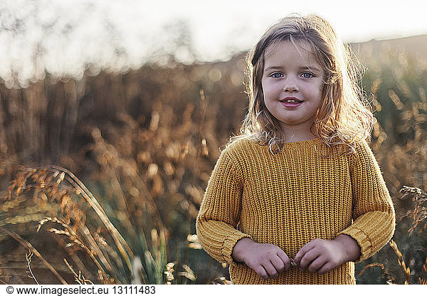 Portrait of cute girl standing against plants at farm