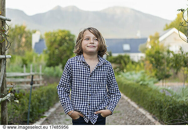 Portrait of eight year old boy smiling  hands in his pockets.
