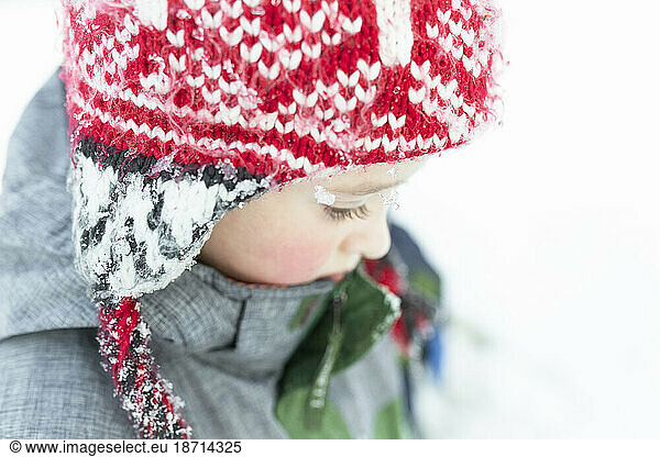 Portrait of elementary age boy wearing red winter hat in the snow