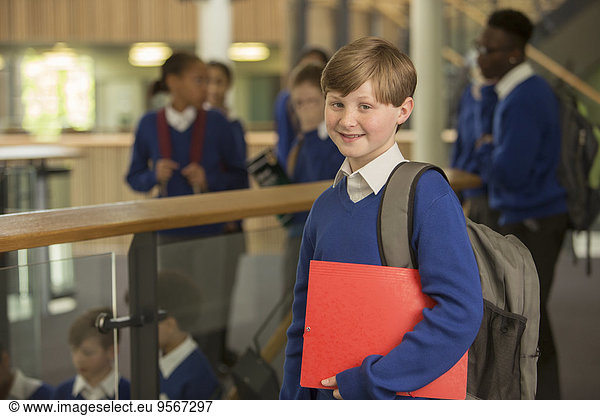Portrait of elementary school boy wearing blue school uniform standing in school corridor