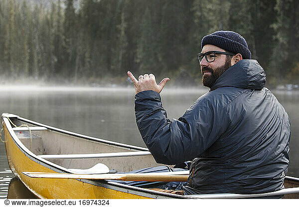 Portrait of excited man canoeing on lake on misty day