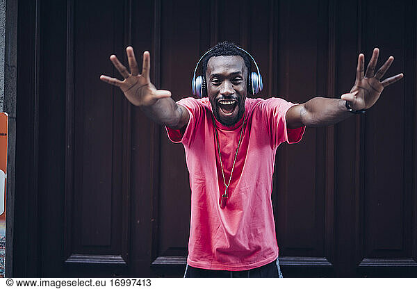 Portrait of excited man wearing pink t-shirt listening to music with headphones