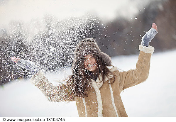 Portrait of excited woman playing with snow