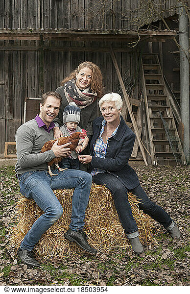 Portrait of family with chicken bird sitting in poultry farm  Bavaria  Germany