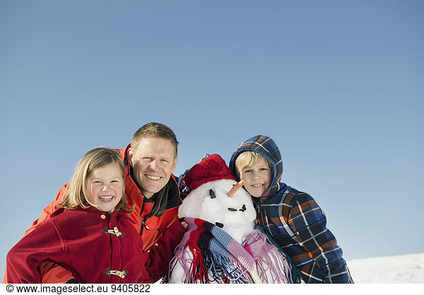 Portrait of family with snowman  smiling