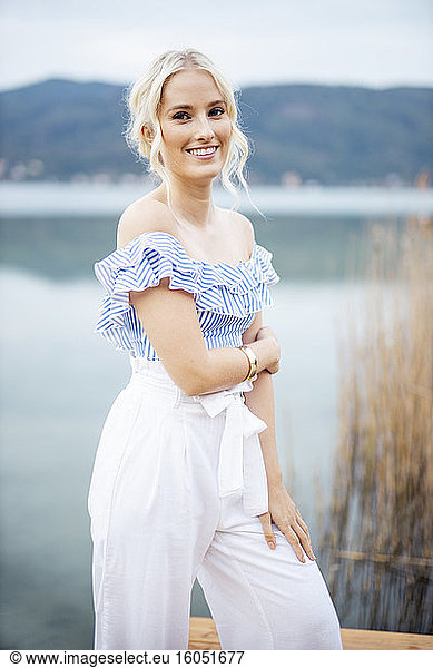 Portrait of fashionable blond woman standing on jetty at Woerthersee  Austria