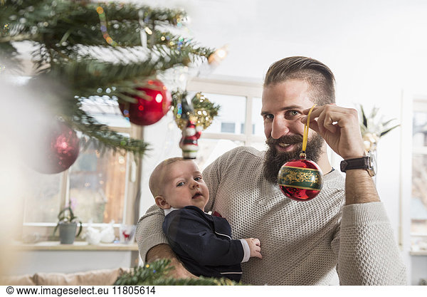 Portrait of father holding baby boy and bauble