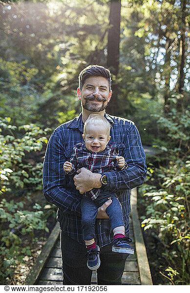 Portrait of father holding his son outdoors.