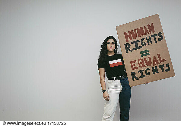 Portrait of female activist with human rights signboard against white wall