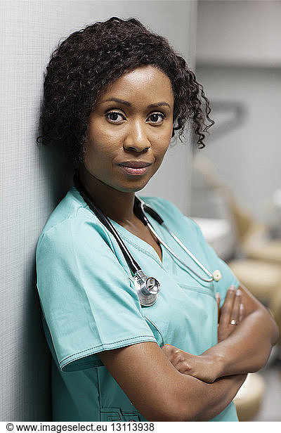Portrait of female doctor standing against wall in hospital