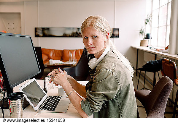 Portrait of female entrepreneur sitting on chair in workplace