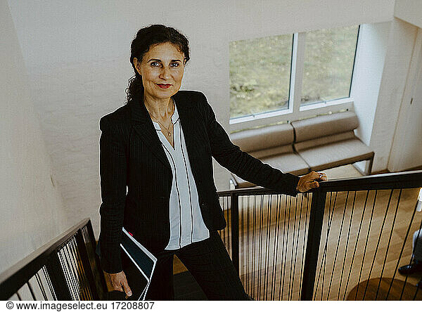 Portrait of female entrepreneur standing on steps at office