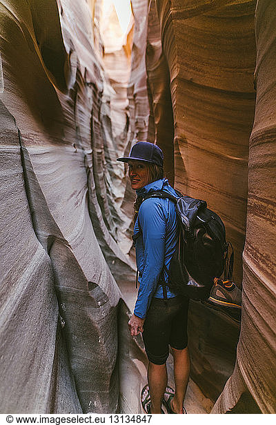 Portrait of female hiker with backpack standing amidst narrow canyons