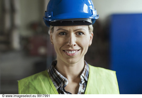 Portrait of female manual worker wearing hardhat in factory
