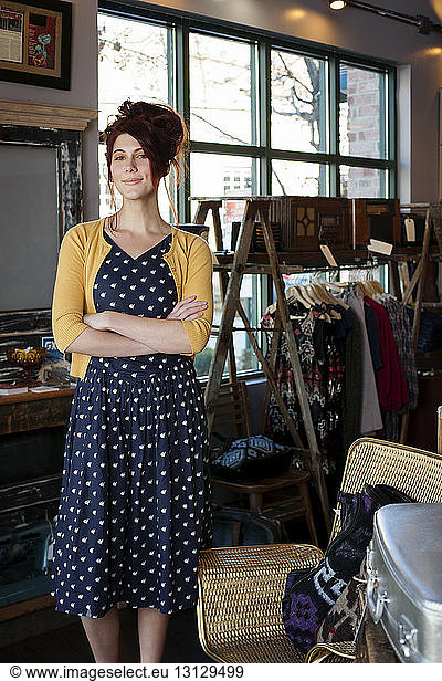 Portrait of female owner with arms crossed standing in clothing store