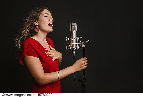 Portrait of female singer with microphone  wearing red dress