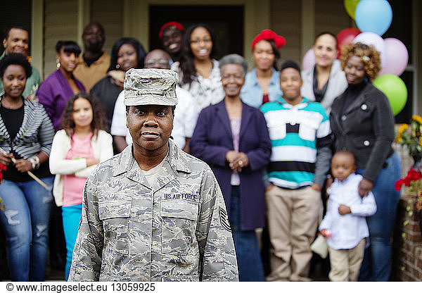 Portrait of female soldier standing against family