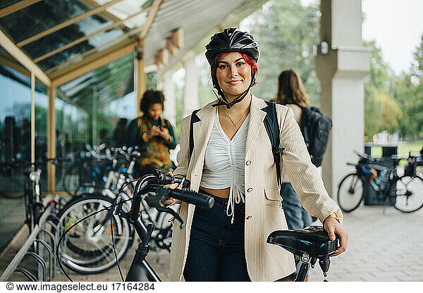 Portrait of female student with bicycle at university campus