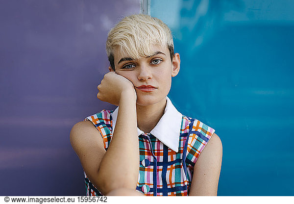 Portrait of female teenager wearing colorful dress leaning on multicolored glass pane