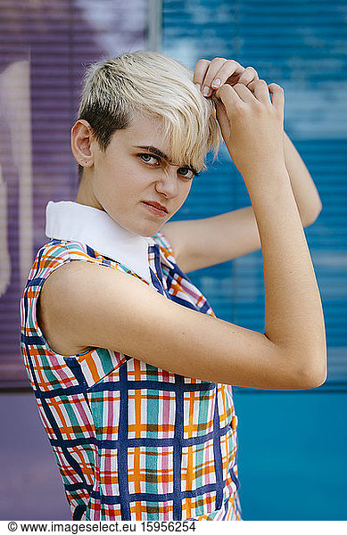 Portrait of female teenager wearing colorful dress with multicolored glass wall in the background
