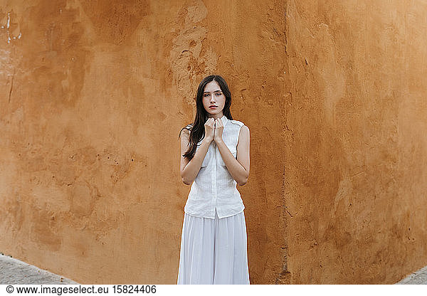 Portrait of female teenager wearing white clothes in front of a brown wall