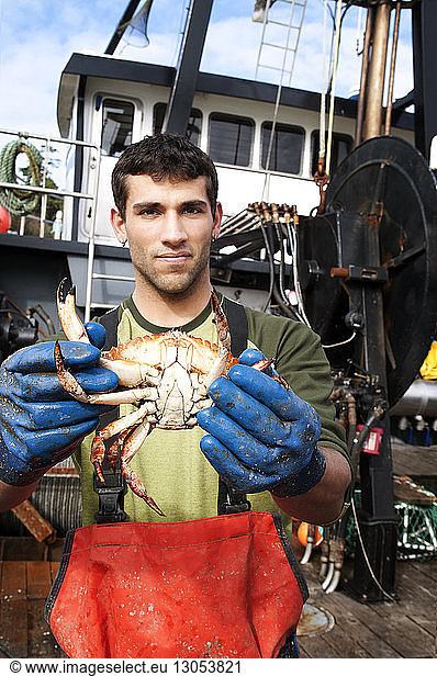 Portrait of fisherman holding crab and standing on boat