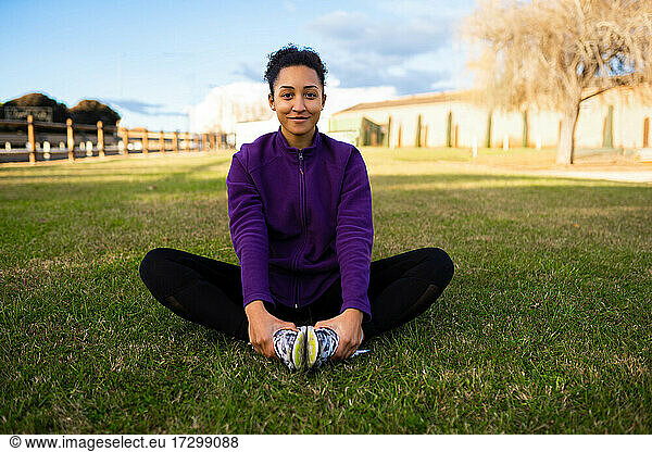 Portrait of fit and sporty young woman smiling doing stretching