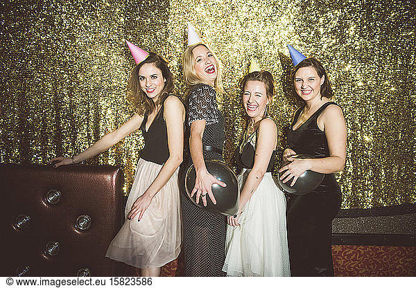 Portrait of four happy women wearing party hats in a club