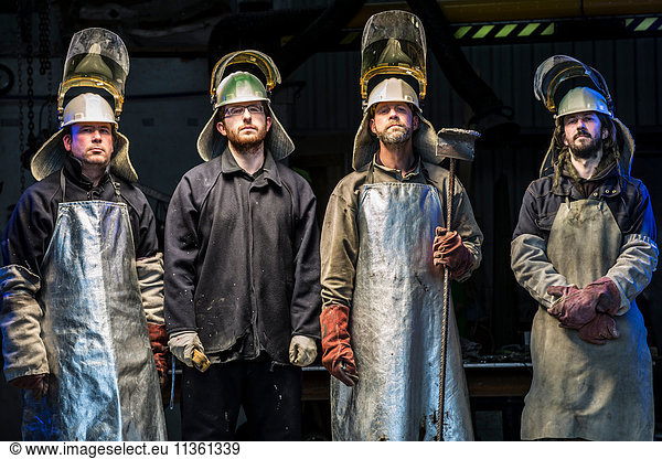 Portrait of four male foundry workers wearing protective clothing in bronze foundry