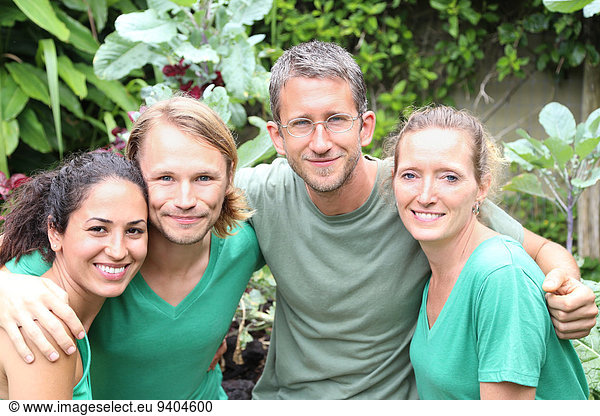 Portrait of four men and women wearing green t-shirts in garden