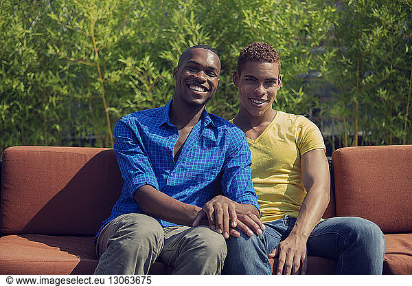 Portrait of gay couple sitting on sofa in lawn