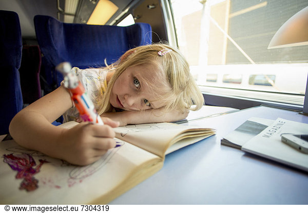 Portrait of girl drawing pictures while sitting on train's seat
