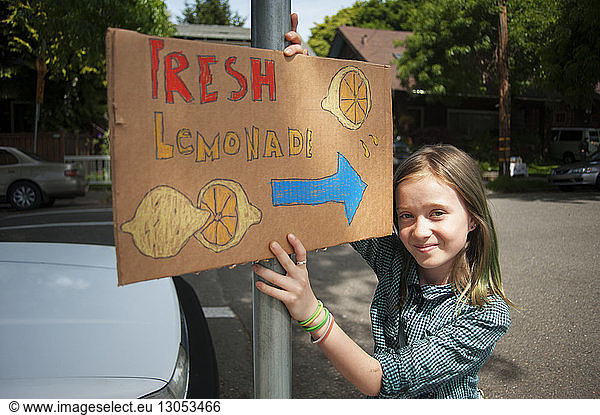 Portrait of girl holding sign board on street