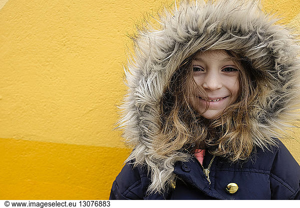 Portrait of girl in fur jacket against yellow wall
