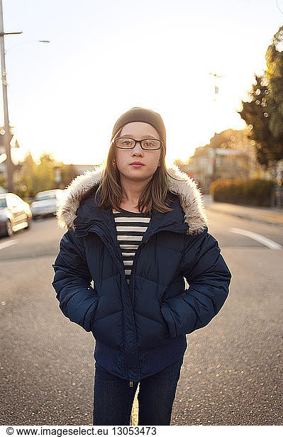 Portrait of girl in warm clothing standing on road against sky