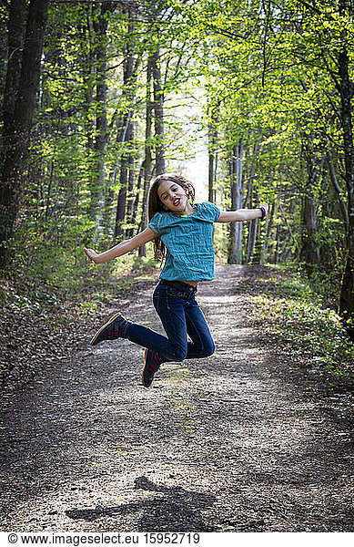 Portrait of girl jumping in the air on forest track
