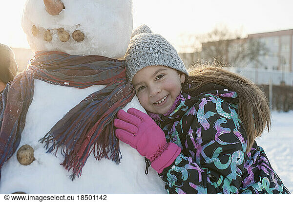 Portrait of girl leaning on snowman