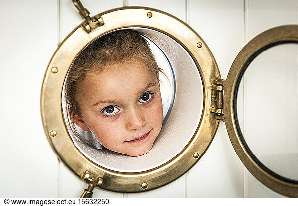 Portrait of girl looking through porthole
