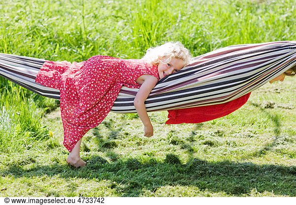 Portrait of girl lying in hammock in field
