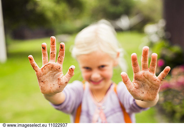 Portrait of girl showing her dirty hands in garden