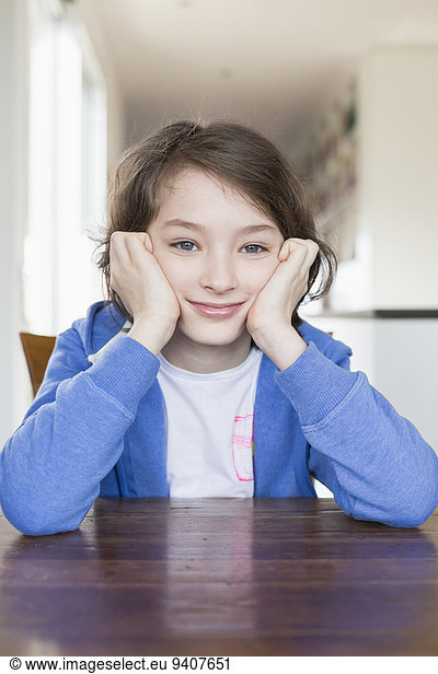 Portrait of girl sitting at wooden table  smiling
