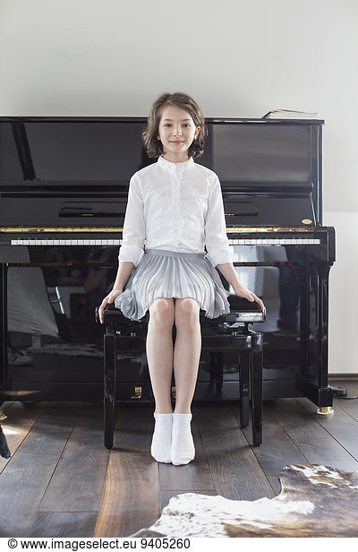Portrait of girl sitting infront of piano  smiling