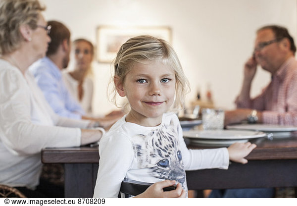 Portrait of girl sitting with family at dining table
