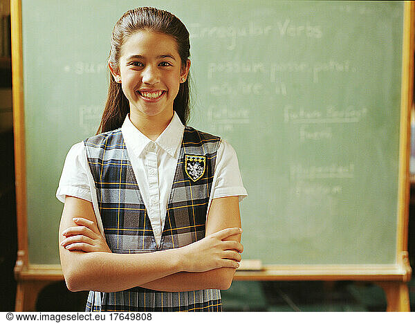 Portrait of girl (10-11) standing in front of chalkboard