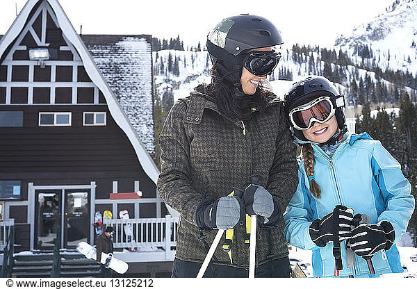 Portrait of girl standing with mother at ski resort