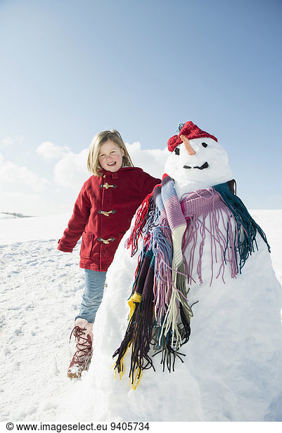 Portrait of girl standing with snowman  smiling